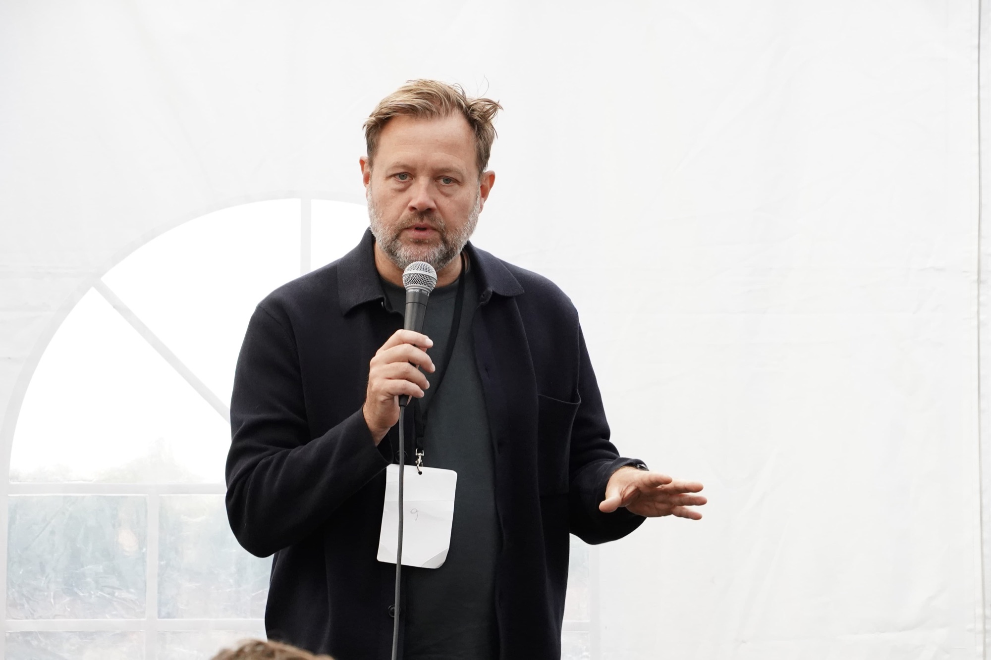 A Social Design Framework track leader speaks into a microphone inside the Rebuild2 tent.
