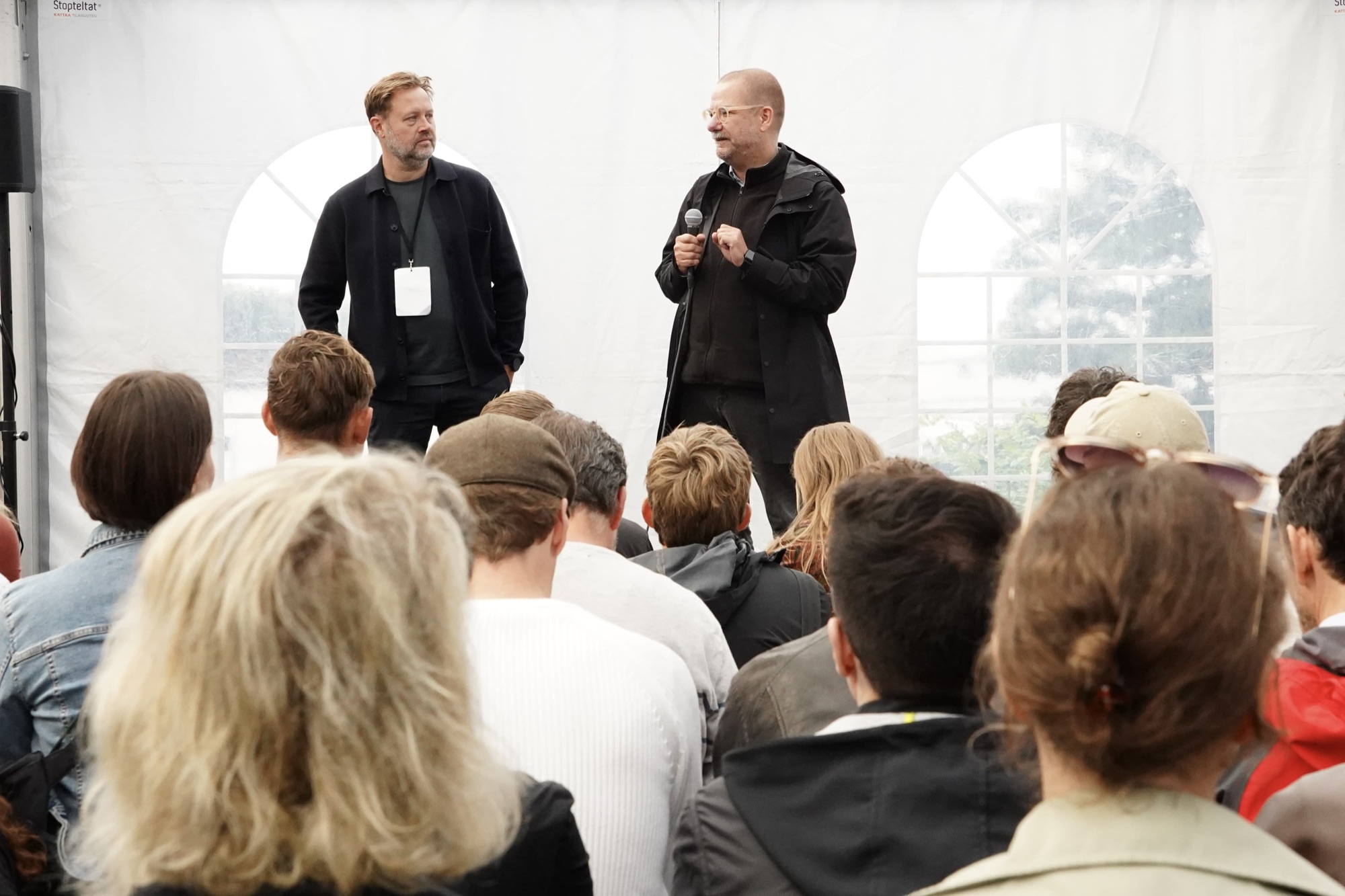 Two Social Design Framework track leaders address a seated audience inside the Rebuild2 tent.